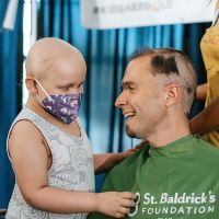 child with facemask helping to shavee a gentlemans hair