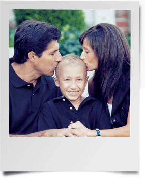 Mother and father kissing young sons bold head